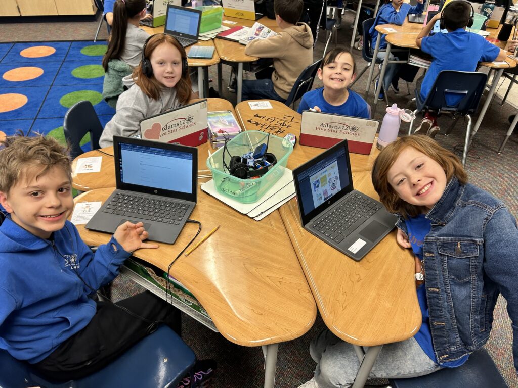 Students in Kristin Schneiders class sit at tables and select their Book Trust books on laptops.